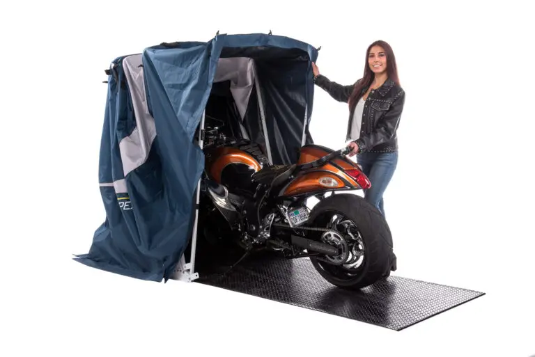Rider rolling an orange sport bike into an open Speedway motorcycle shelter