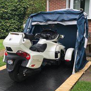 customer image of a deluxe speedway shelter with floor in a backyard open with a white 2017 CAN-AM® SPYDER® RT 6-SPEED SEMI-AUTOMATIC inside with extra room