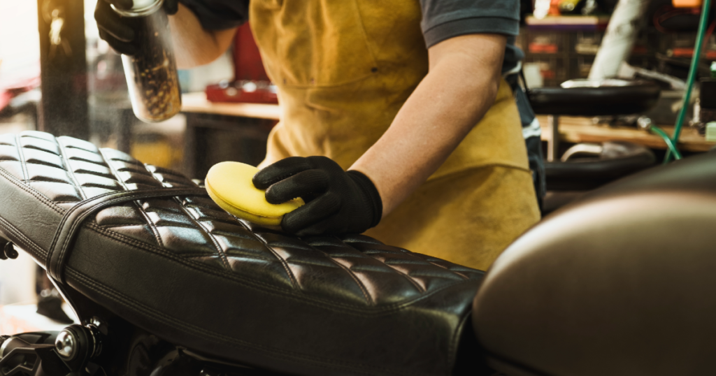 applying leather conditioner to motorcycle seat in a workshop to prepare for winter storage