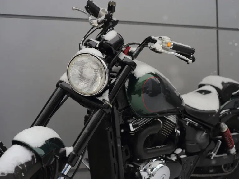 Snow on the seat, tank and fender of a cruiser motorcycle parked outside