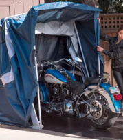 female biker closing the touring speedway shelter over a blue harley davidson motorcycle