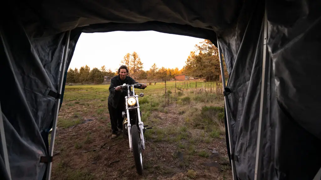 View from inside an open Speedway motorcycle storage shelter as a rider rolls in