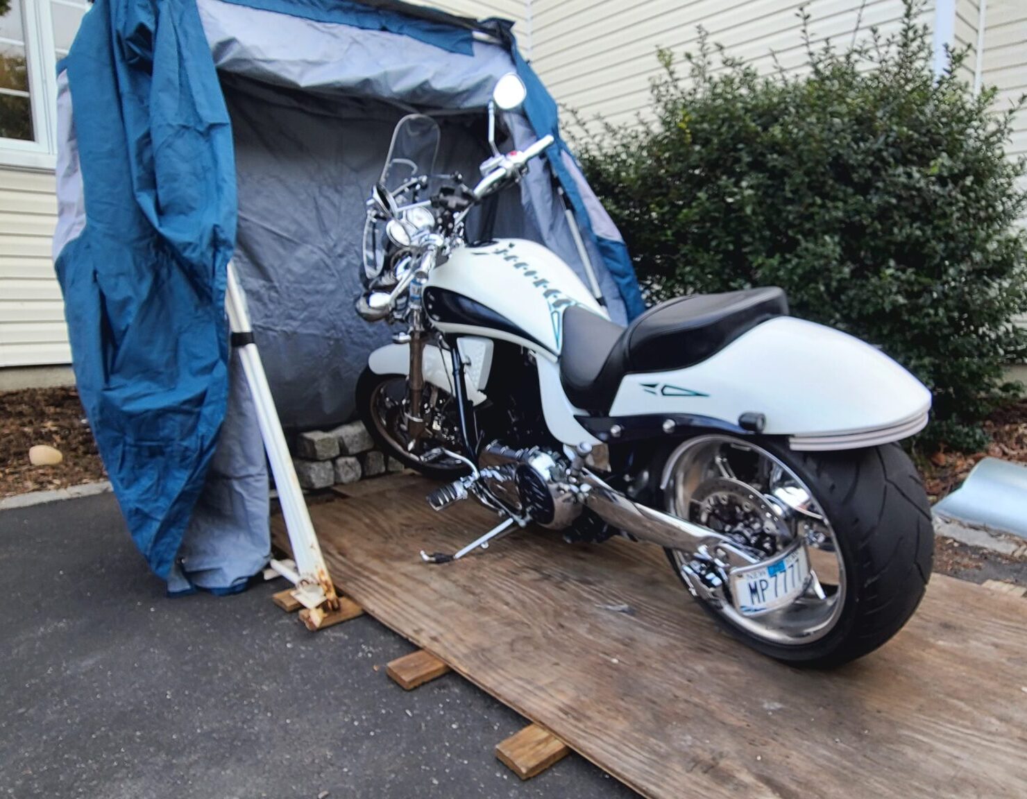 White cruiser motorcycle parked in an open Speedway Shelter on a wooden base