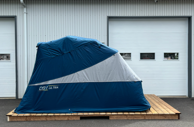 Deluxe Speedway Shelter on a wood platform in front of a garage