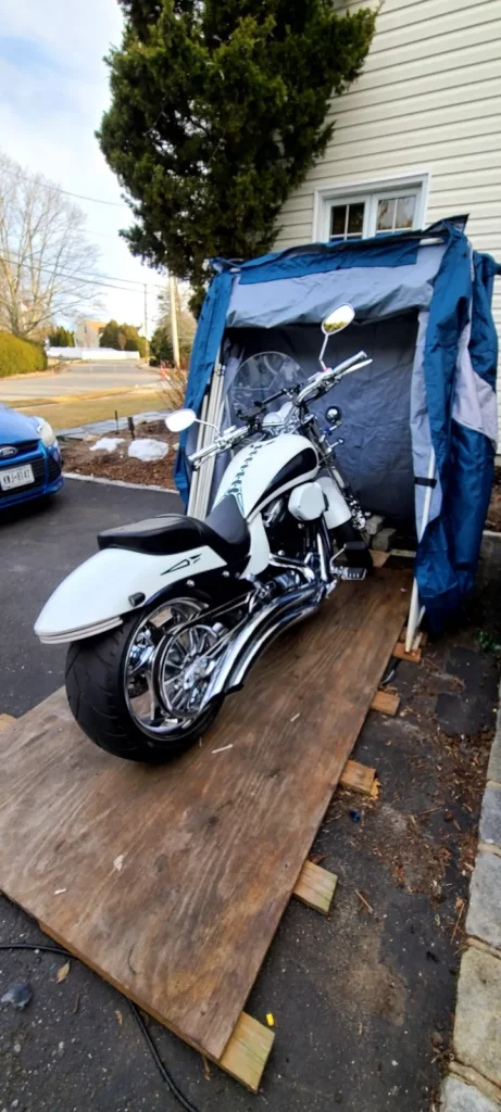 White cruiser motorcycle in an open Speedway Shelter on a wooden base