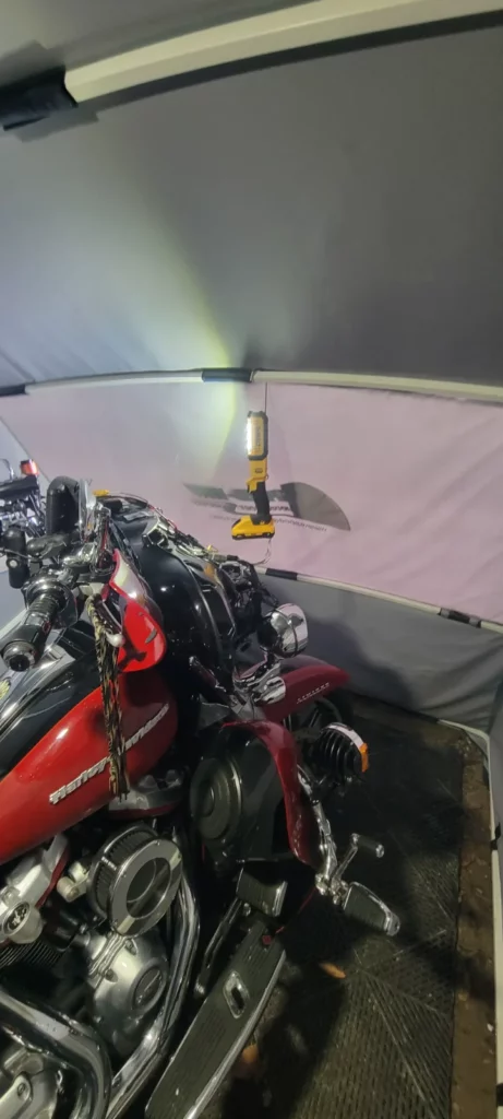 Red Harley-Davidson touring bike inside a Speedway Shelter lit up as a winter workshop