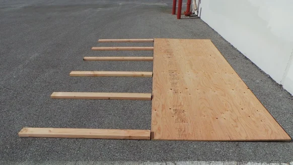 Pressure-treated 2x4s laid flat across the width of a motorcycle shelter wood base